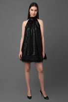 Woman wearing a black sequin dress against a gray background