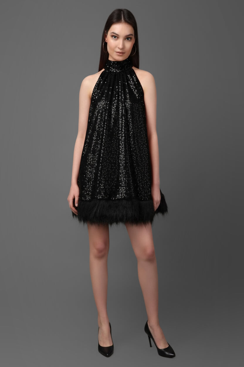 Woman wearing a black sequin dress against a gray background