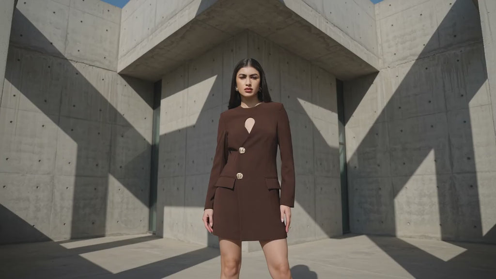 Woman wearing a brown dress against a gray wall