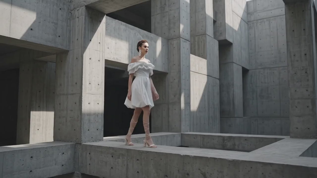 Woman in a white dress standing in a concrete architectural setting