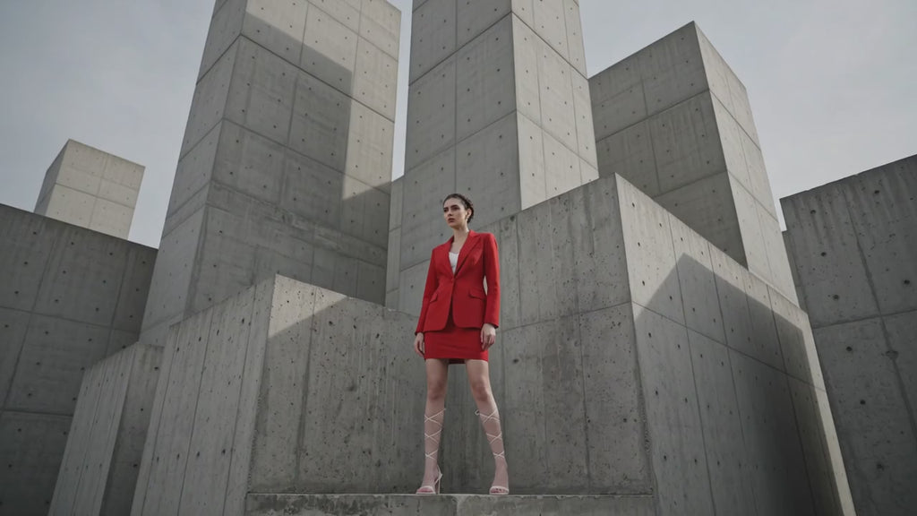 Woman in a red outfit standing in a concrete architectural setting