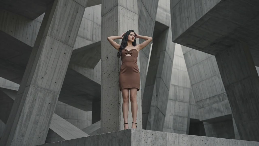 Woman in a brown dress standing in a geometric concrete structure