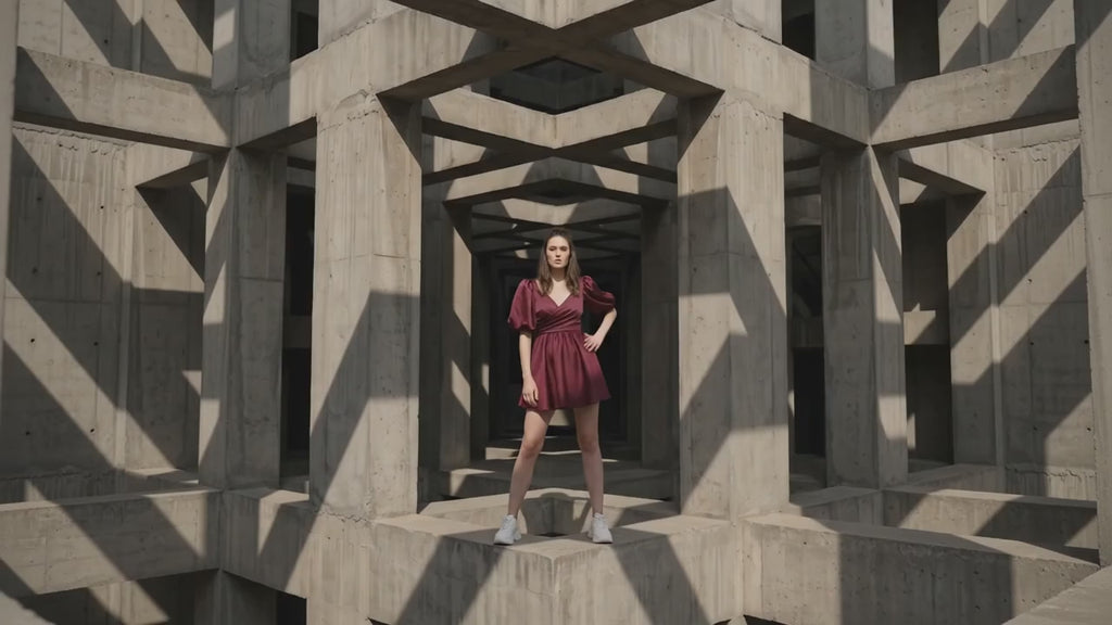 Woman in a burgundy dress standing in a concrete indoor setting